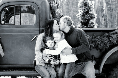 Family sitting on truck with parents kissing | Family Photography Session