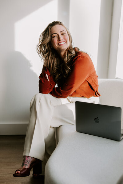 Website copywriter Erika Fitzgerald sitting in a studio next to her laptop, showcasing her Showit website