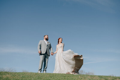 Bride and Groom hug and laugh surrounded by their bridal party. Bride has a flower crown and groom is in  a black tux. Anna Brace, a wedding photographer omaha nebraska