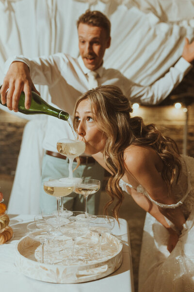 Wedding couple celebrating by drinking champagne from a champagne tower at a Seattle wedding, photographed by Bare Bones Photo