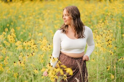 a high school girl standing in a field of wild flowers