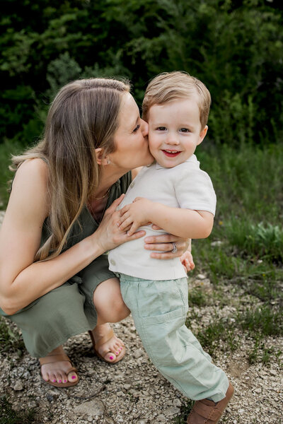 mom and dad kiss newborn baby boy in dallas texas home photo session