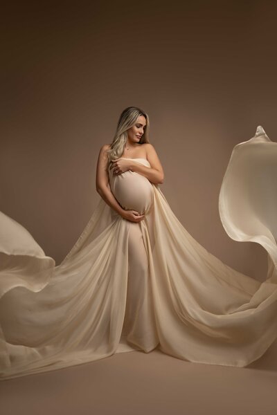 Maternity Session of blonde pregnant Mom with a flowing cream drape dress. Photograph taken by Jenni Nikki who serves greater Atlanta, Georgia.