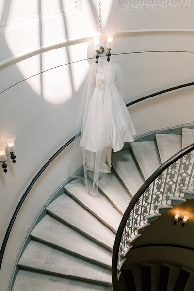 A silk wedding dress hangs from the balcony of a spiral staircase in Washington DC