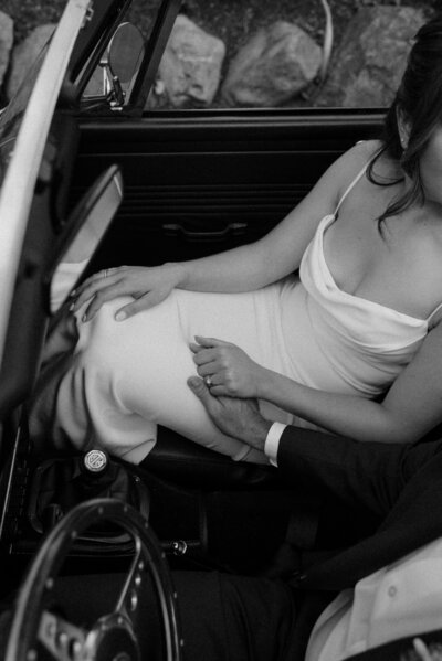 Close-up of a bride and groom holding hands in a vintage car, a cinematic moment in documentary-style Seattle wedding photography.