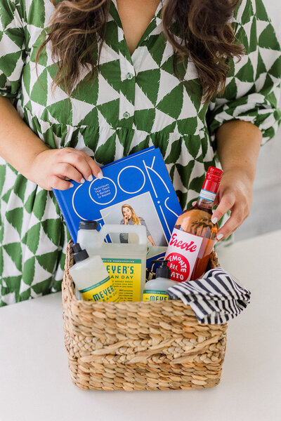 Marissa Martinez in a green and white dress putting together a basket of cleaning supplies and books