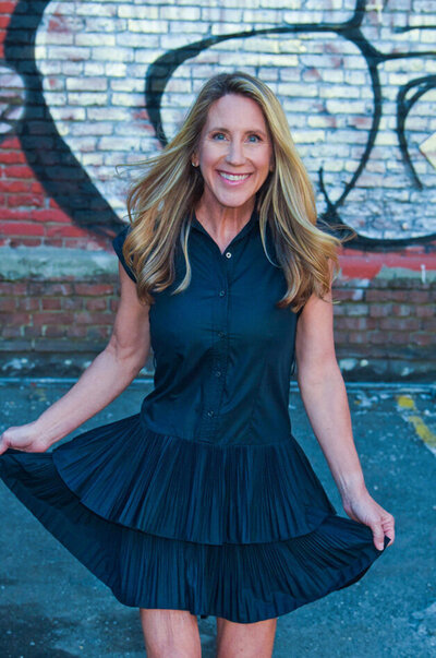 Kristy Clarke poses for a photo in a stylish black dress, smiling confidently at the camera.