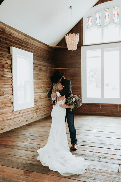 Bride and groom kiss in front of barn