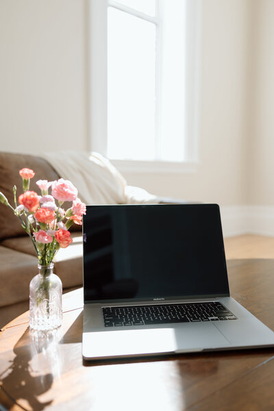 A laptop alongside a vase of flowers, symbolizing the tools and resources social media managers need daily. Sugarpunch Marketing’s resource guide helps social media managers streamline content creation and engagement.