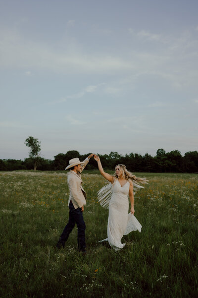 bride and groom dancing in a wildflower field at their oklahoma wedding