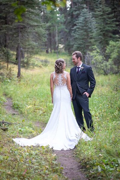 a bride and groom looking at each other in the woods
