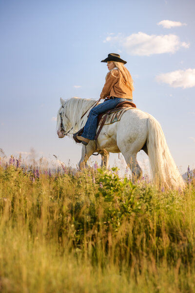 Horse and Rider, riding through field of purple lupine flowers in Montana.