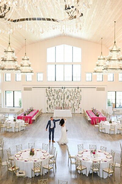 Crystal Chandeliers hang elegantly from ceiling of a beautiful white wedding venue