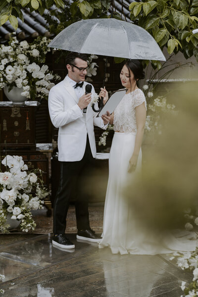 a bride and groom stand under a clear umbrella saying their vows at their wedding ceremony in Seoul, South Korea