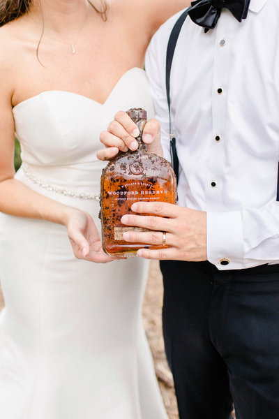 bride and groom holding a bottle of whiskey