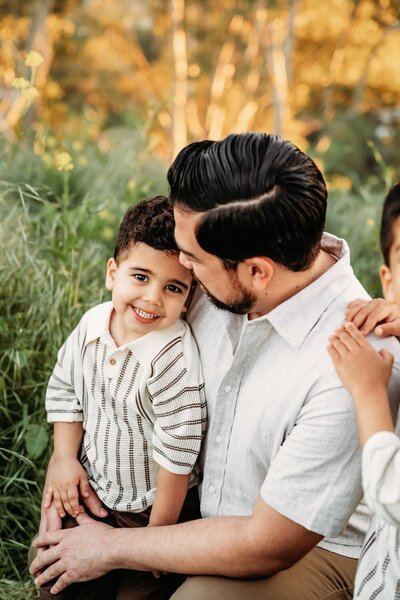 toddler looking at camera smiling while sitting on dads lap