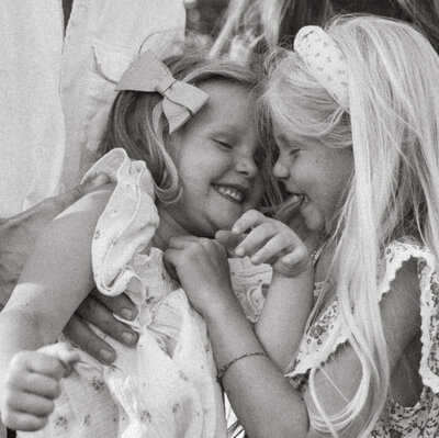 Two sisters laughing together during a family photoshoot in Oregon, captured in a joyful and candid moment amidst the natural surroundings.