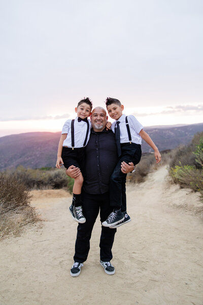 dad holds son in each arm