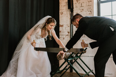 Bride and Groom are sawing a log as part of a ceremony ritual.