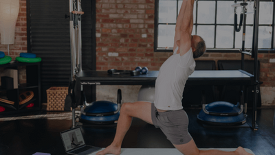 man doing a low lunge in a pilates class 