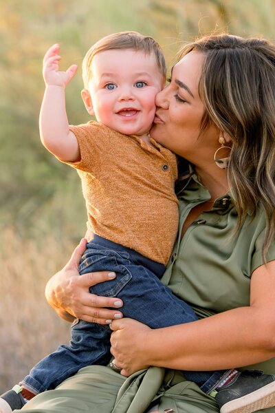 mother kissing son in arizona desert with little boy smiling at camera 