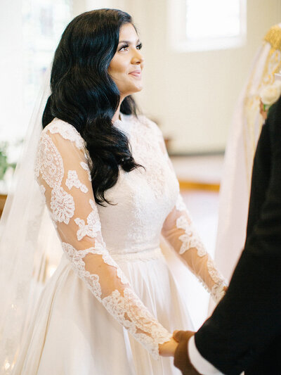 bride with natural makeup and hair down in lace long sleeved wedding dress