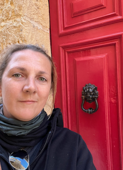 Website designer Helen Nuttall  in front of a red maltese door