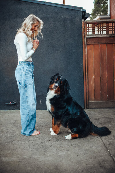 Stephanie, a Portland OR realtor and relocation expert smiles at her dog in her backyard.