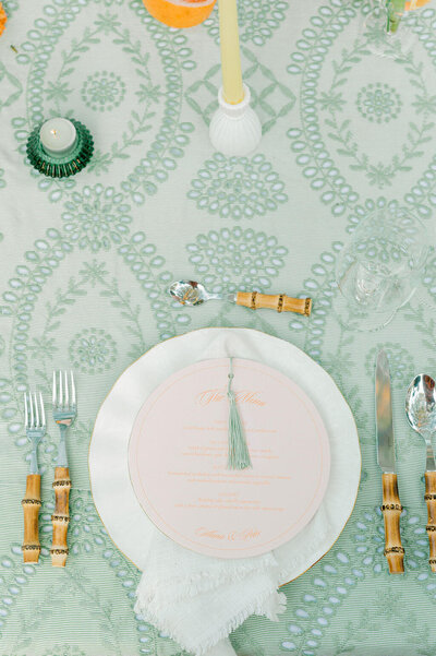 Wedding day stationery menu with tassel detail on blush plate, styled on sage linen.
