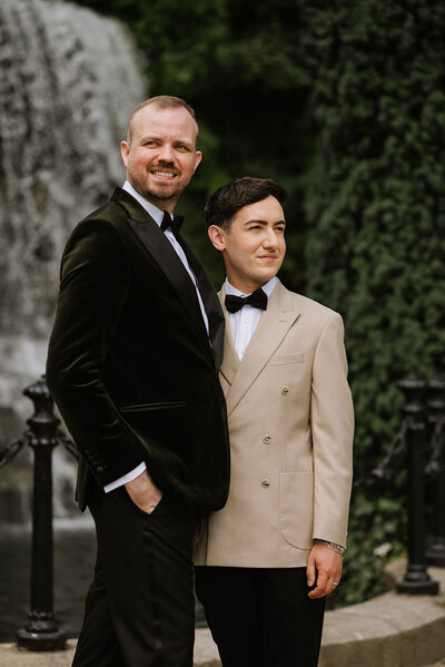 Two grooms smiling in front of a waterfall in Dublin, Ireland