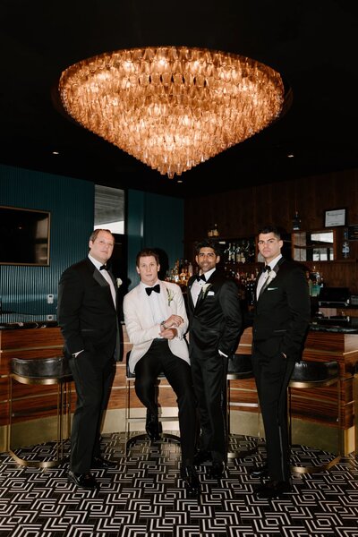A newlywed and their wedding party sitting at a bar 