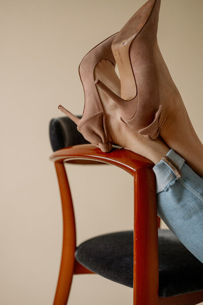 Woman rests her high heels on the arm of a chair