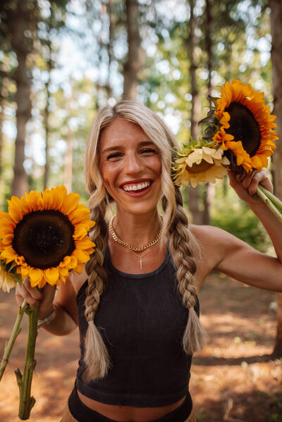Blonde woman in  with braids holding sunflowers in nature