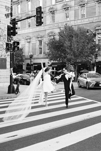 Bride and groom running across street in Baltimore, taken by one of the top baltimore wedding photographers Nicole Simensky