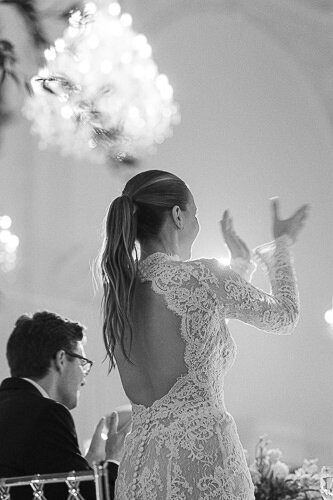 Une mariée debout qui applaudit lors de la réception de mariage.