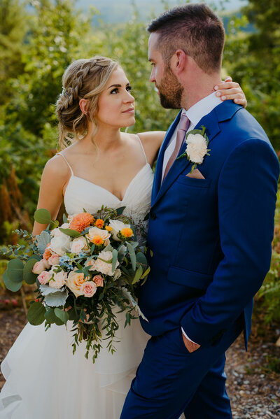 bride and groom outdoors with orange and pink bouquet