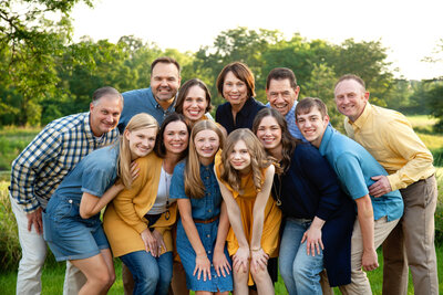 Extended family leaning in close together smiling.
