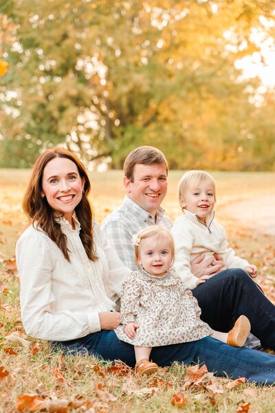 Family portrait by Chattanooga family photographer, Kelley Hoagland.  Family sits in leaves and smiles.