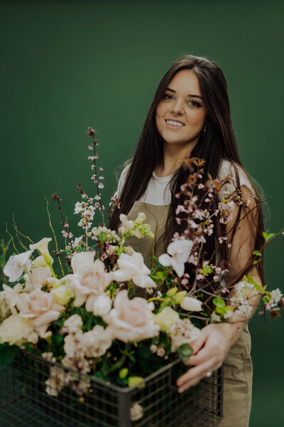 Bride with veil posed in front of dark green woods holding bridal bouquet