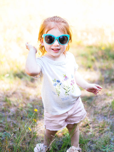 toddler in teal sunglasses strikes a pose