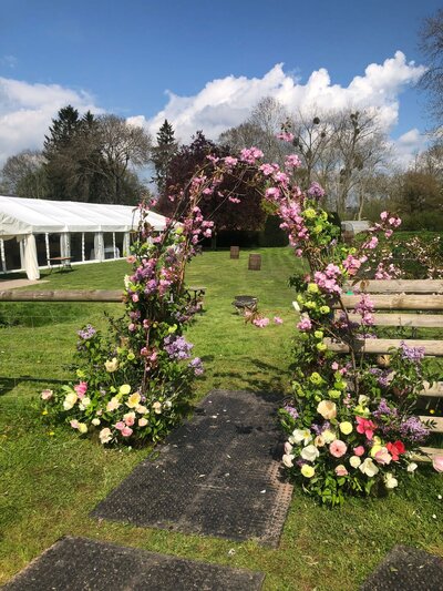 freestanding spring arch of flowers to welcome guests to the marquee using pink blossom