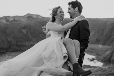 black and white image bride and groom embracing on beach during their elopement on the west coast