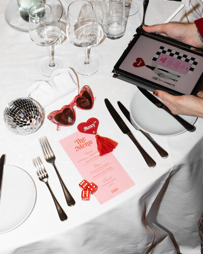 Pink, retro wedding menu and wedding guest name tag with a disco ball and dice next to it