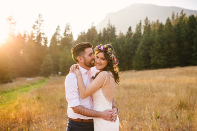 Bride and groom running in a field at sunset