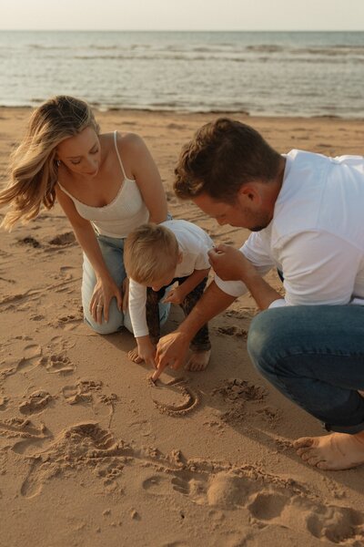 mom dad and son play on beach during lifestyle photos in pei