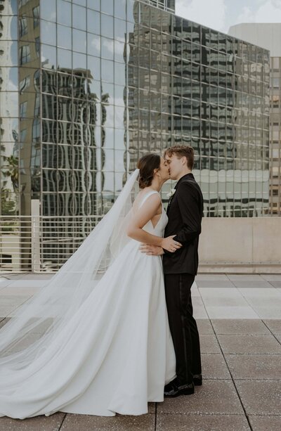 Bride and groom posing in front of a glass building
