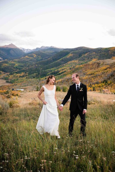Elopement Photographer, Bride and Groom walking in a mountain meadow