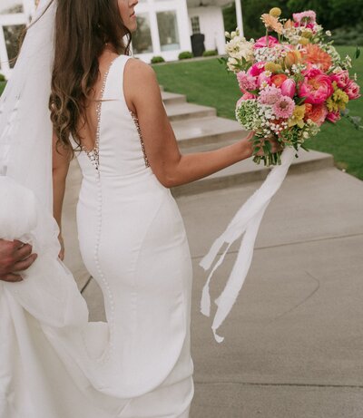 bride walking away from her camera holding her bouquet
