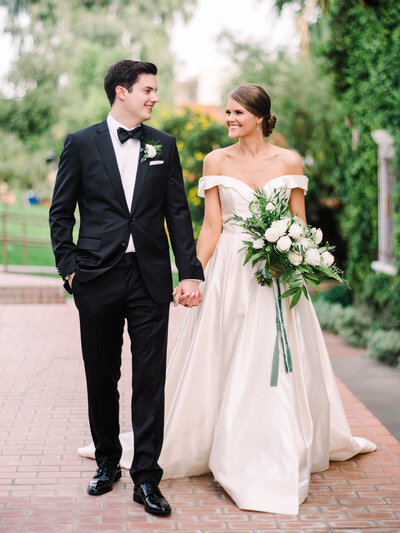 bride holding lush white bouquet walking with groom