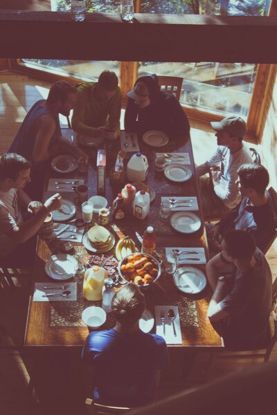 Group of people sitting around a wooden table sharing a meal